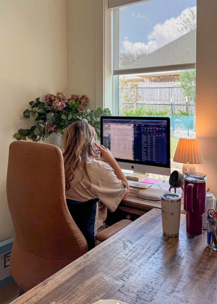 A woman at her desk on the phone, working at her computer in a home office
